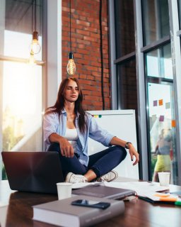 Frau meditiert auf dem Tisch im Konferenzraum